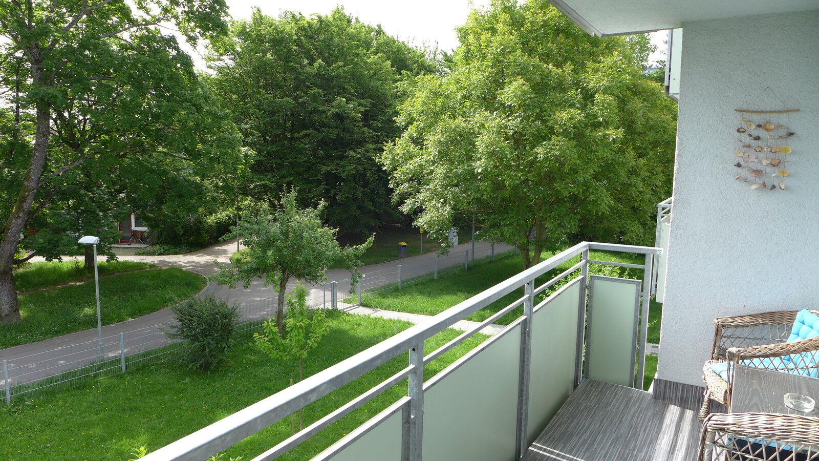 Aussicht von einem Balkon über den angrenzenden Gehweg ins Grüne