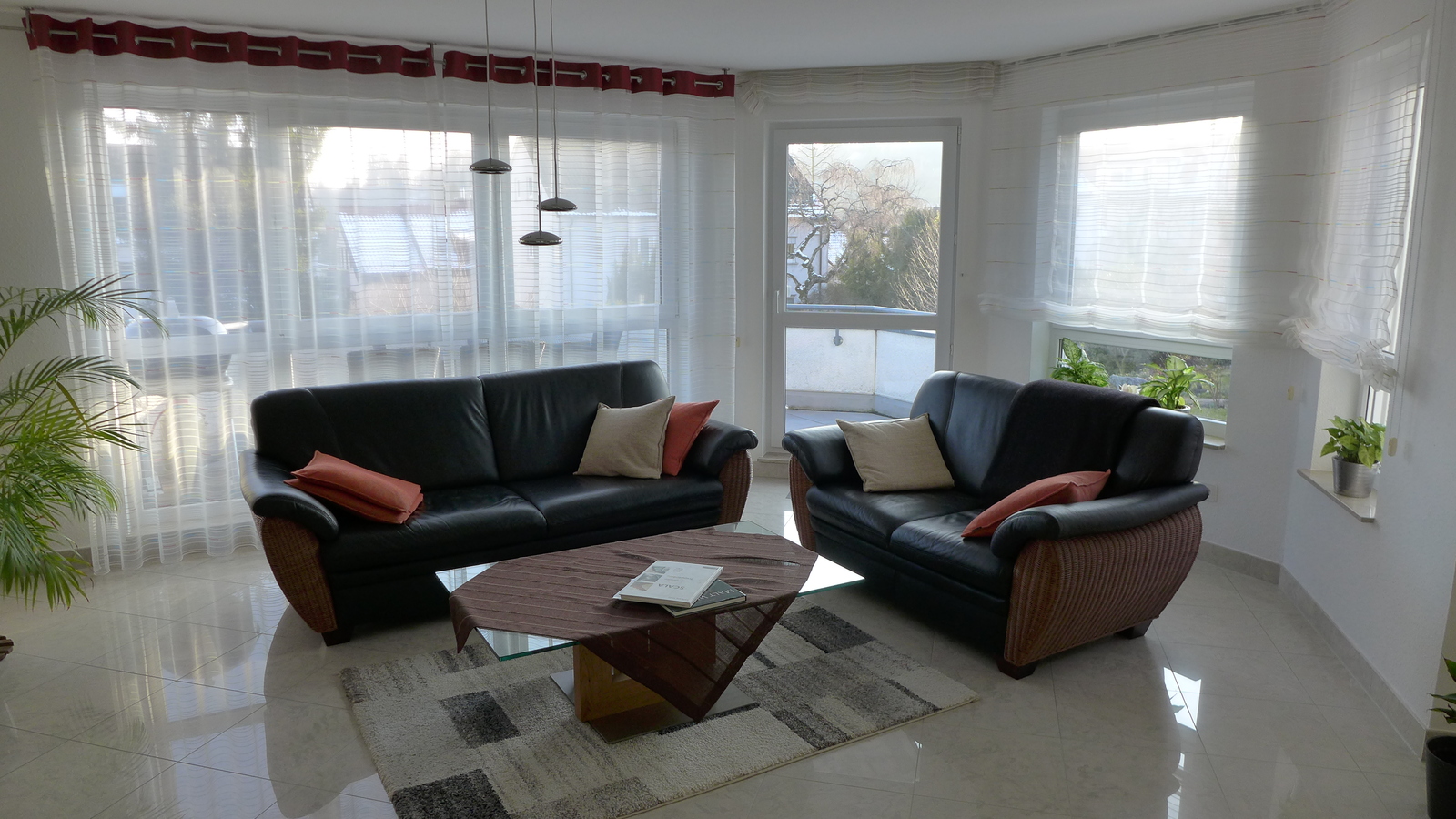 Eingerichtetes Wohnzimmer mit modernen Möbeln und Balkon im Hintergrund